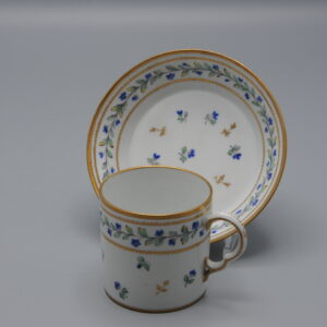 Cup and saucer in the style of Chantilly porcelain, bearing faux Chantilly marks, attributed to the Samson manufactory, Paris, 19th century. The decoration is hand-painted in the "Décor Barbeaux" pattern, consisting of scattered cornflowers (Centaurea cyanus) and other botanical elements. The Barbeaux décor was originally developed by the Sèvres Manufactory in the late 18th century for Marie Antoinette, reflecting a preference for naturalistic floral designs associated with the Queen’s taste. This style was used primarily on hard-paste porcelain produced at Sèvres beginning in the 1780s. The form and decoration of the cup and saucer closely follow the late 18th-century models, with gilded accents applied to the rim and handle. The cup stands 6 cm high; diameter 5,5 cm (ex the ear) . Both pieces exhibit signs of wear consistent with age. Pseudo mark Chantilly Samson - Porcelain Cup and Saucer decor 'Aux Barbeaux' - late19th century French