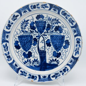 18th-Century Dutch Delft Blue and White Dish with Grapevine An 18th-century Dutch Delftware dish painted in cobalt blue with three prominent bunches of grapes growing from a stylised vine. Smaller grapes, leaves and curling tendrils fill the central field, while the border is divided into panels of stylised floral motifs and scrolling ornament. The dish retains an old collection label numbered 546. Tin-glazed earthenware. Unmarked. Delft, the Netherlands, 18th century. Provenance: Formerly in the collection of Henri Blay (1861–1920). Condition: Small chips, glaze losses and scratches around the rim, consistent with age. Diameter: 30.5 cm.