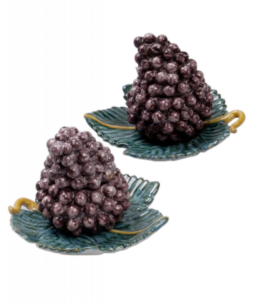 Pair of Dutch Delftware Grape Tureens Naturalistically modelled as bunches of manganese-purple grapes, each tureen is fitted with a conforming cover and rests on a separate stand shaped as a green vine leaf with yellow details. The curling stems form the handles. These playful, sculptural covered dishes were intended as striking elements on the eighteenth-century dining table. Dutch Delftware, second half of the 18th century. Dimensions: 12.5 × 16 cm each.