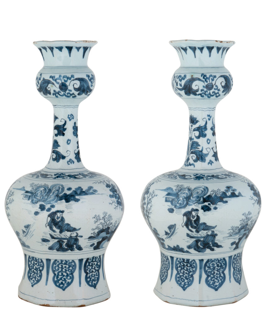 Pair of Blue and White Dutch Delftware Garlic-Neck Vases A pair of octagonal blue and white Dutch Delftware garlic-neck vases, each with a bulbous body supported on a spreading foot and a tall, slender neck with a pronounced knop beneath the flaring trumpet-shaped mouth. The vases are painted in the Transitional style with continuous narrative scenes of Chinese figures in a landscape with trees, rocks and vegetation. This type of decoration was inspired by Chinese porcelain produced during the transitional period between the Ming and Qing dynasties. Delft potters adapted these porcelain designs to the larger, strongly articulated forms of Dutch faience. Delft, circa 1670. Height: 36 cm.